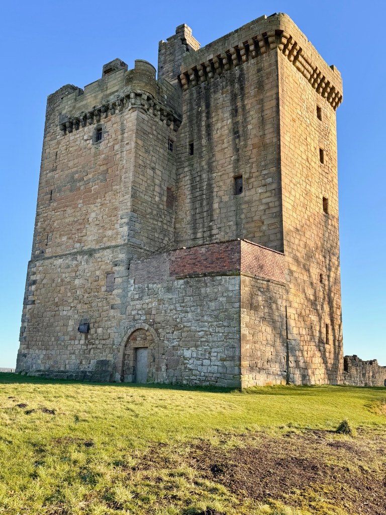 Back of the structure, showing the L-shape layout. Arched doorway at bottom. Bright sunlight on south wall.