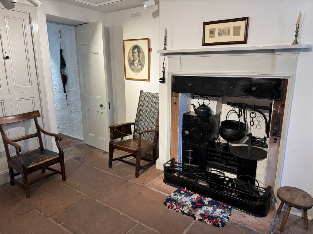 What walled room, with fireplace housing black pots, kettle and stove. Tiled floor 