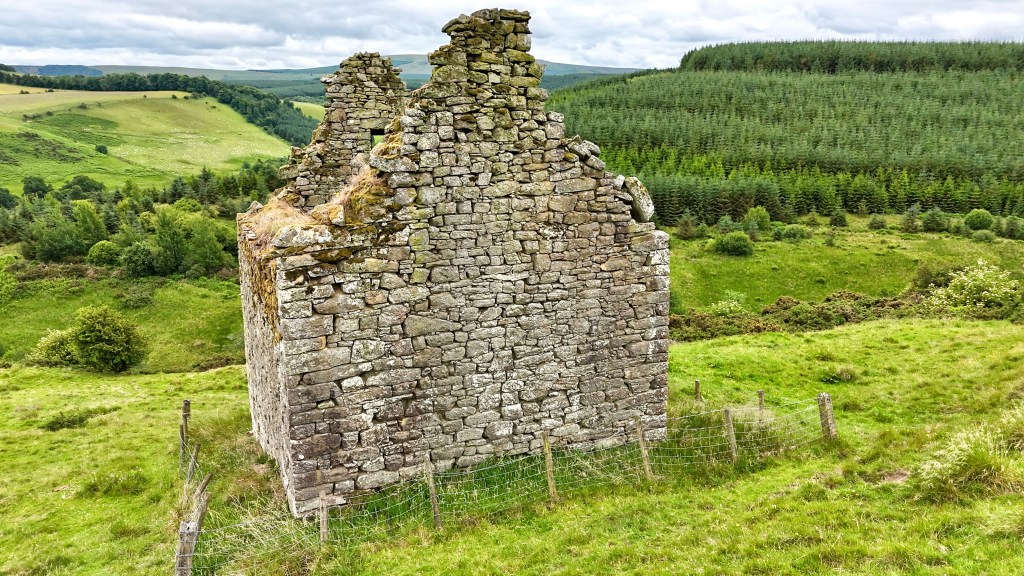 View from the north east showing the gable end. The valley falls away below, with a forested area on the right.