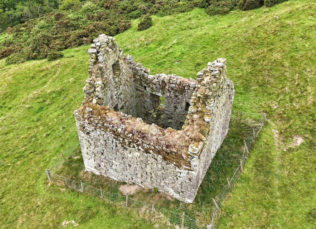 Drone shot looking down on the tower from the north east. The thick walls are clearly visible. The gable ends are both prominent.