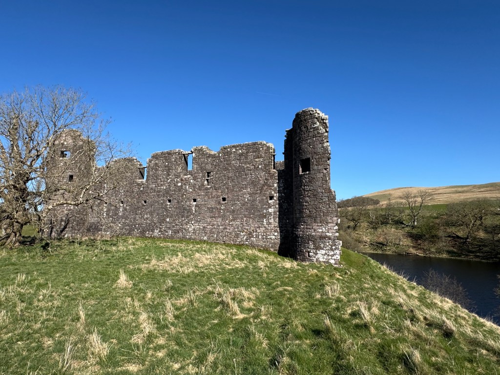 Castle perched on the steep hill, with the loch below to the right.