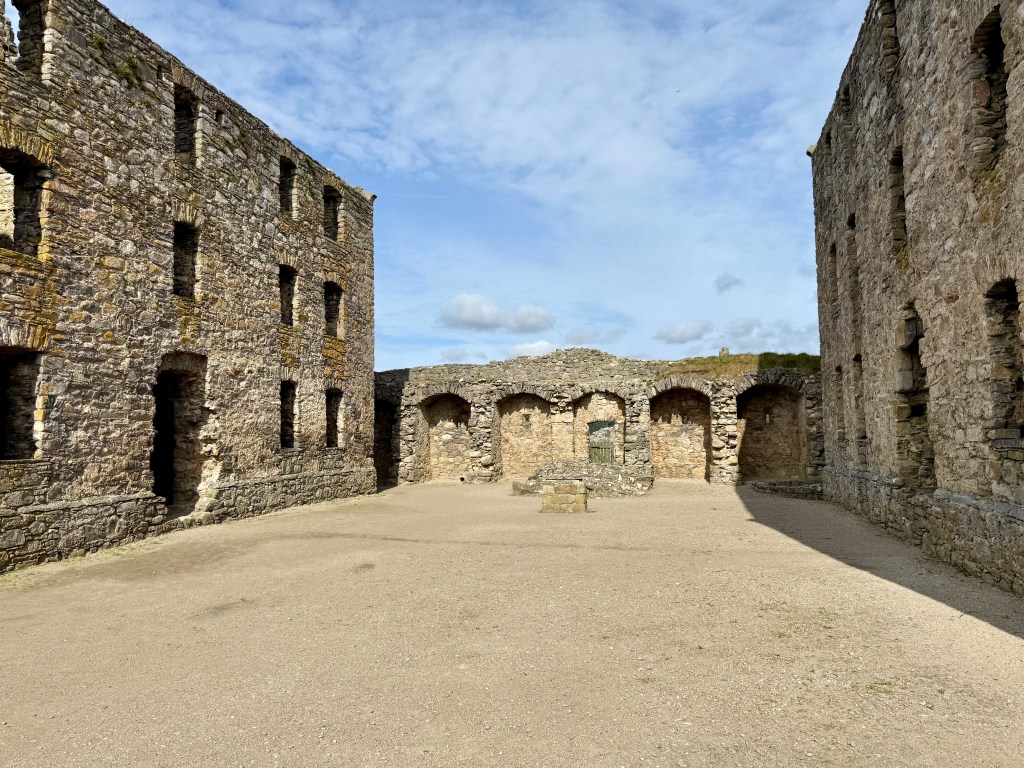 Open space surrounded by barrack bloacks left and right, with wall at far end.