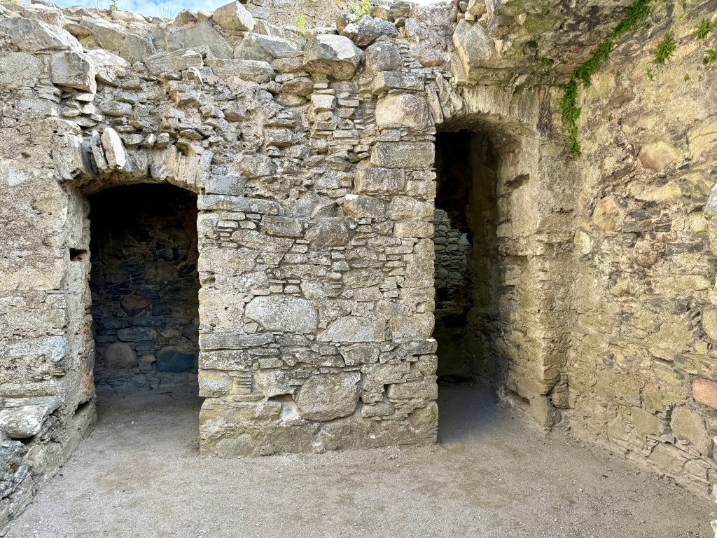 Two openings in wall, shown in close-up, built with grey-brown rubble stone