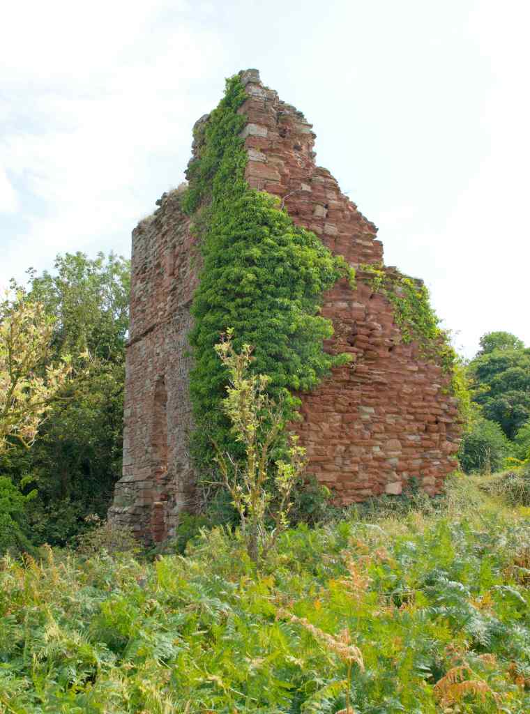 ground level view of west wall, built from red sandstone. It falls away leftwards.