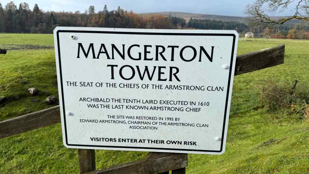 Information sign for Mangerton Tower, saying that tenth laird was executed and providing date of 1999 when site was restored by Armstrong Clan Association.