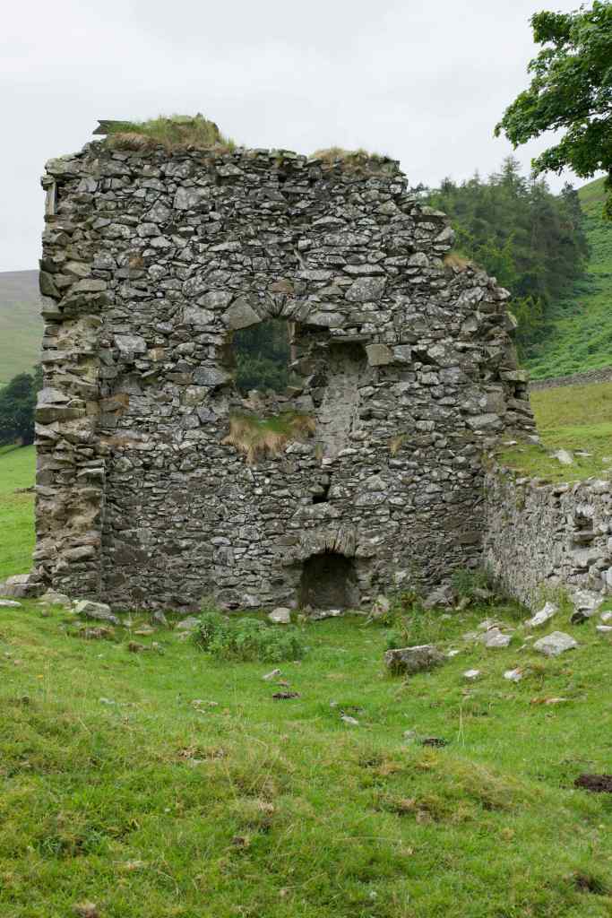 via the outbuilding wall from the north side, showing an opening with an archway at ground level.