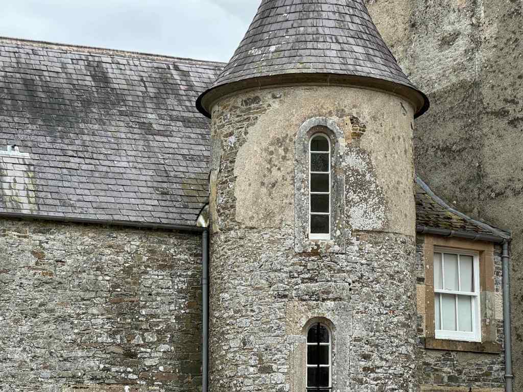close up of turreted tower, showing old stone work and narrow windows.
