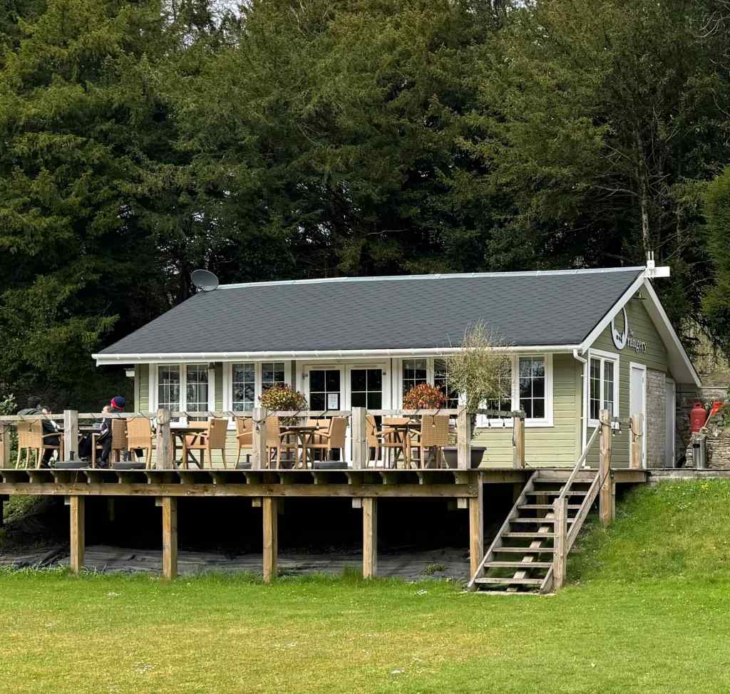 The Orangery, sitting on its decking. A wooden structure painted pale green with a pitched roof.
