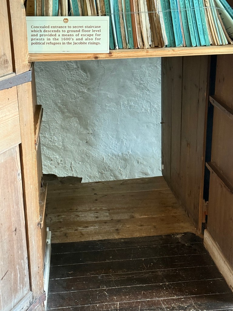 close-up of secret exit to stairs under a bookcase, behind a wooden door