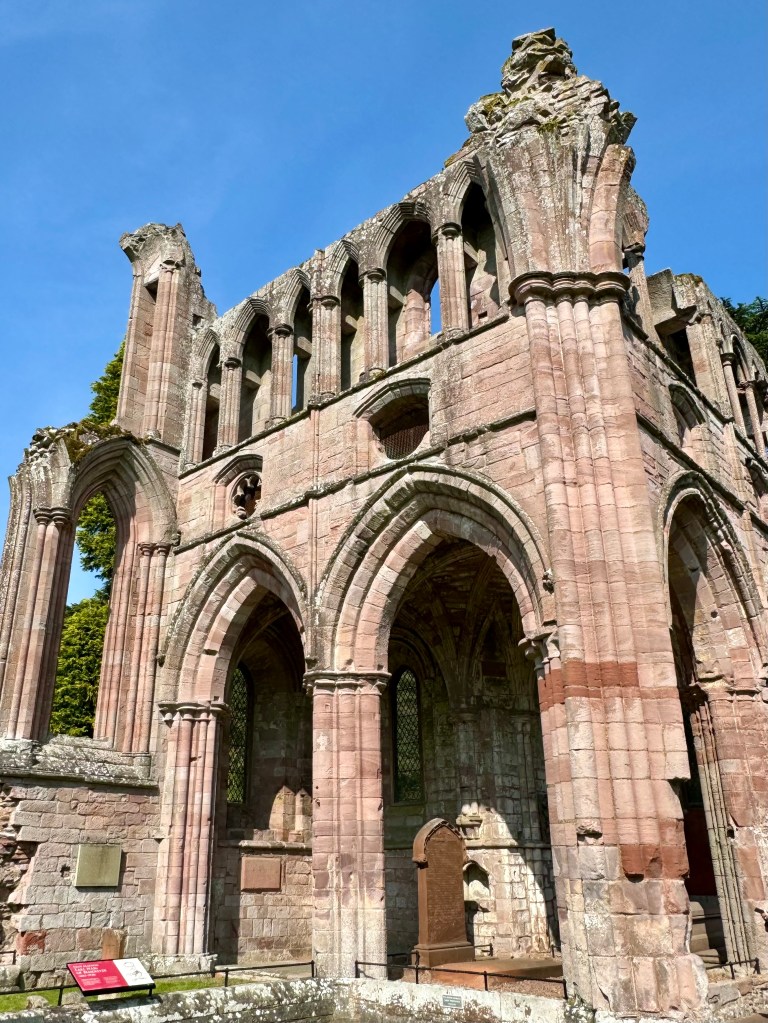 Tall structure with two main arches in the main view and a third at the side. Gravestone and plaques visible