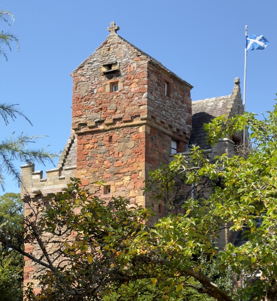 The tower is visible behind the cap house, and a saltire flies from the flagpole.