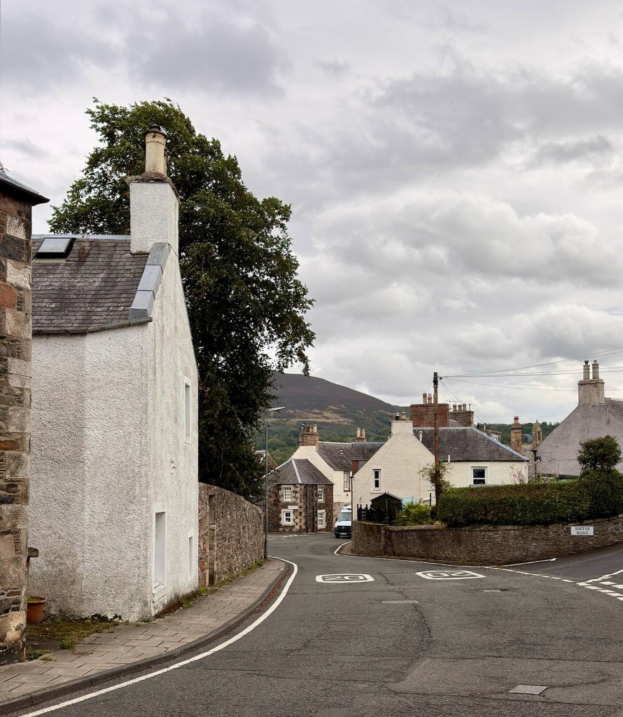 View of image village street. White houses and stone-brick walls.