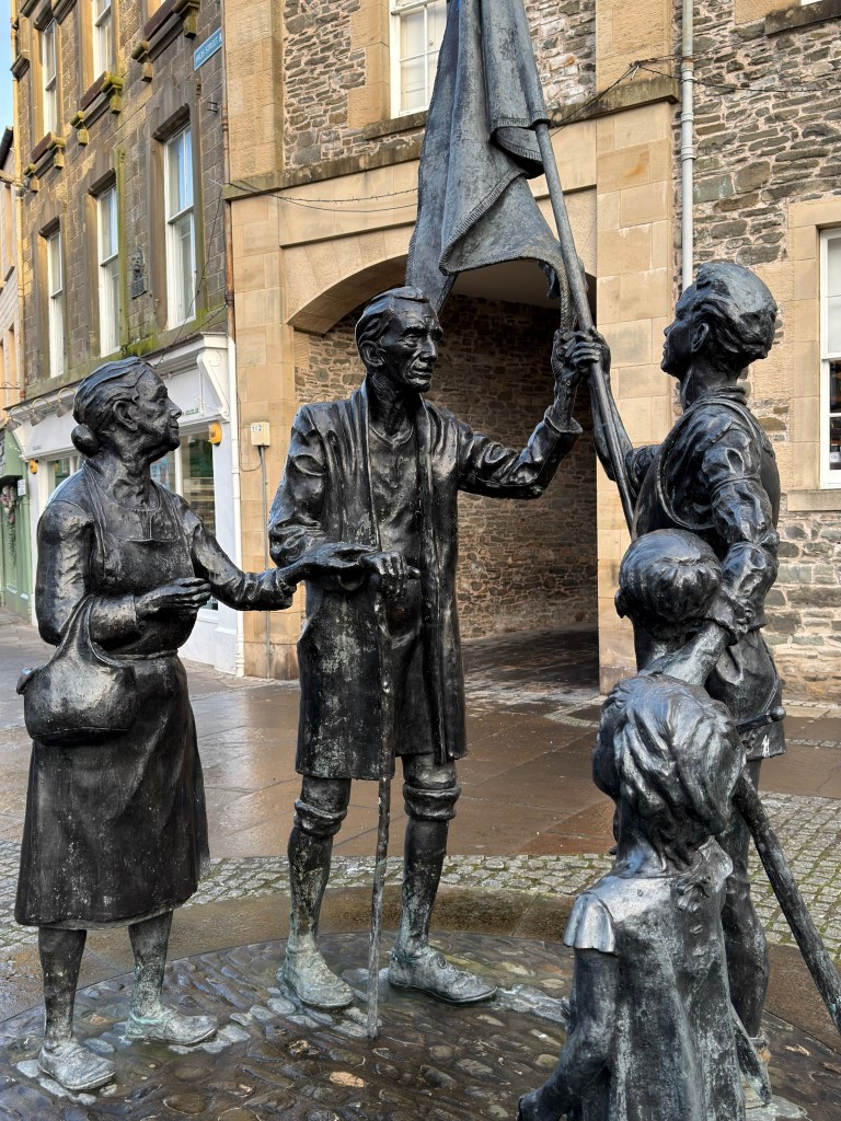 Memorial showing a young man carrying a flag being greeted by townsfolk.