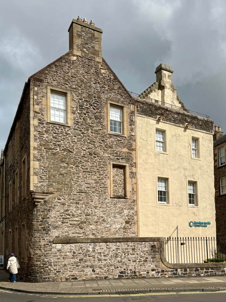 View of the building's western side. The right-hand side has been rendered, but the left is uncovered stonework.