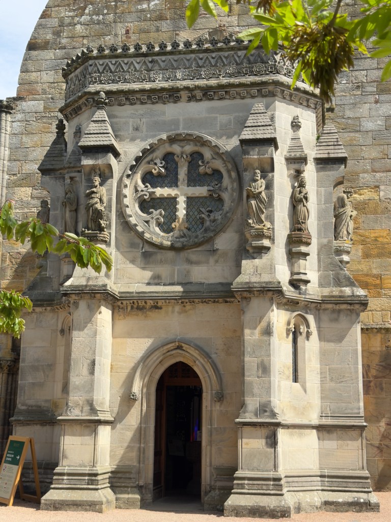 The west entrance, showing exterior carvings of religious figures and an elaborate cross above the door.